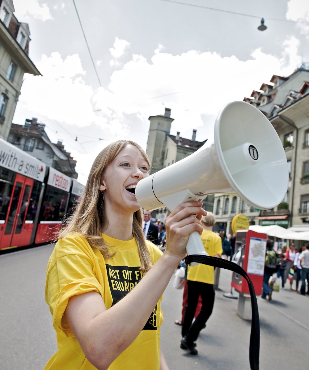 Eine Frau mit einem Amnesty-T-Shirt ruft in ein Megafon