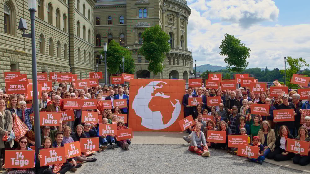 Aktivist*innen und Mitglieder des Komitees stehen mit Plakate für die Konzernverantwortungsinitiative vor dem Bundeshaus.