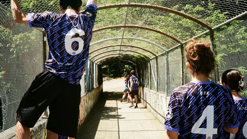 Die Mitglieder des FC Hardegger posieren von hinten in ihren schwarz-violett gestreiften Trikots.