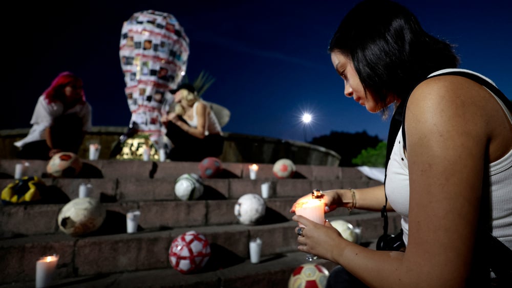 Eine Frau zündet vor einem provisorischen Denkmal, das die Weltmeisterschaft darstellt, in Mexiko eine Kerze an.