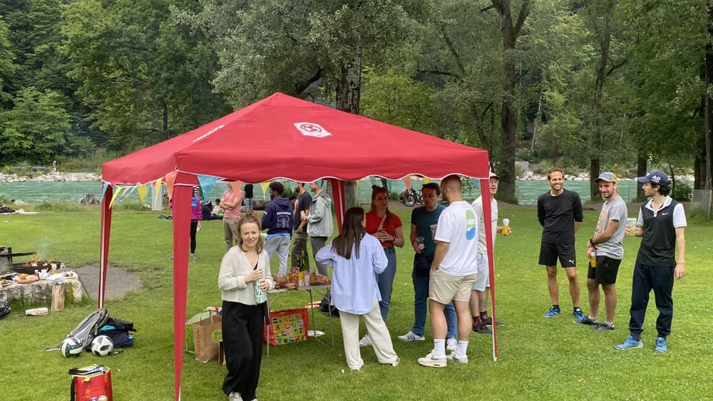 Die Mitglieder des IFCB und ihre Partnerinnen veranstalten ein Grillfest am Flussufer.