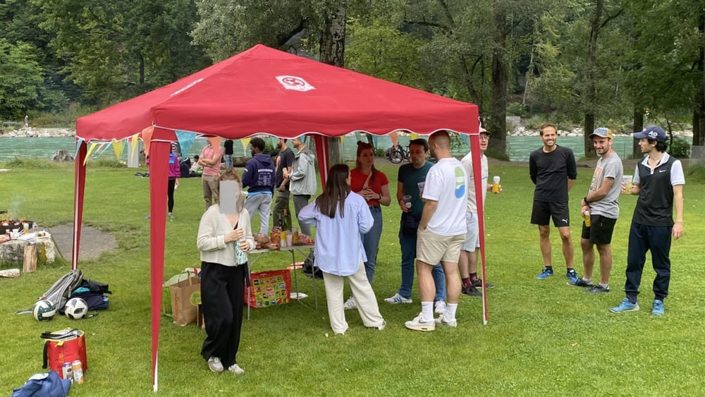Die Mitglieder des IFCB und ihre Partnerinnen veranstalten ein Grillfest am Flussufer.