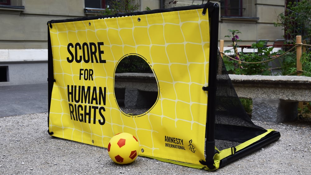 Ein junger Mann und eine junge Frau stehen im Fifa-Museum vor dem WM-Pokal mit T-Shirts auf denen Justice for Workers steht.