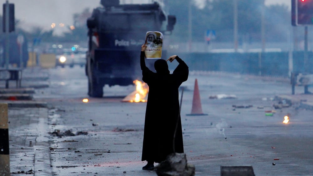 Eine Demonstrantin mit einem Bild eines schiitischen Geistlichen stellt sich vor bewaffnete Polizeiwagen.© REUTERS/Hamad I Mohammed