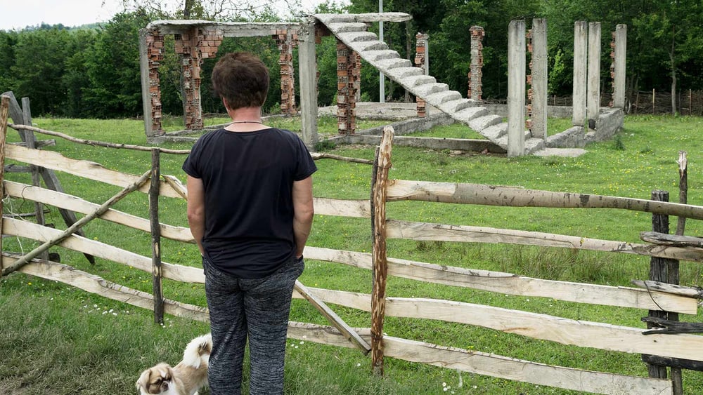 Eine Überlebende in Osten von Bosnien betrachtet ihr zerstörtes Haus. Staatliche Unterstützung und Hilfsprogramme kommen oft kaum bis in die ländlichen Gebiete © ZIYAHGAFIC