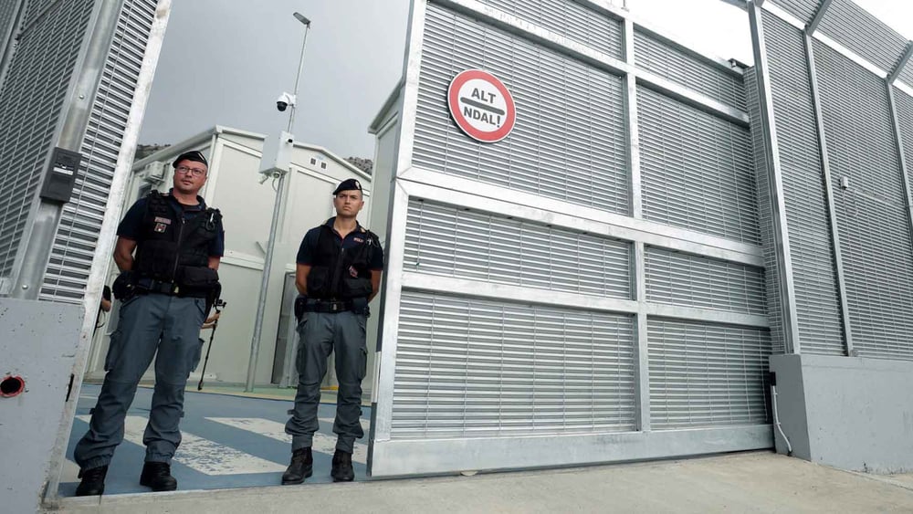 Italienische Polizisten stehen am 11. Oktober 2024 am Eingang eines kürzlich errichteten, von Italien betriebenen Migrant*innenzentrums im Hafen von Shengjin, etwa 60 Kilometer nordwestlich von Tirana © ADNAN BECI/AFP via Getty Images