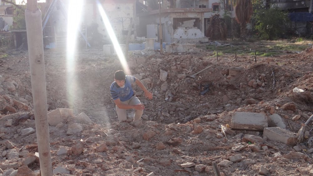 Ein Bewohner von Daraya klettert aus einem Krater, der von einer Fassbombe hinterlassen wurde (Mai 2014) © Local Council of Daraya City