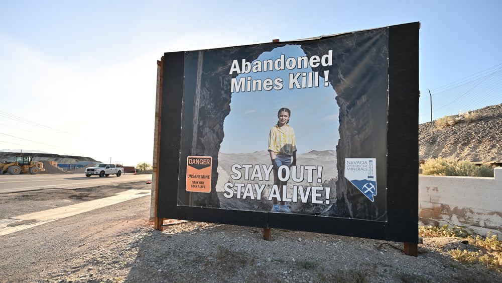 Ein Strassenschild mit einem Kind drauf und der Schrift: Abandoned mines kill. Stay out - stay alive.