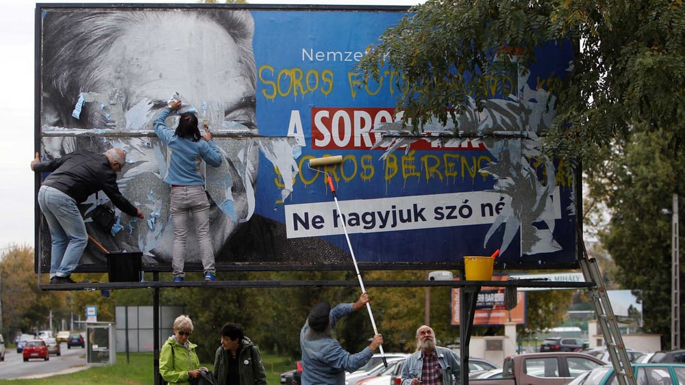 Aktivisten entfernen ein Plakat, auf dem George Soros beschuldigt wird, eine Million MigrantInnen pro Jahr in Europa ansiedeln zu wollen. © REUTERS/Bernadett Szabo