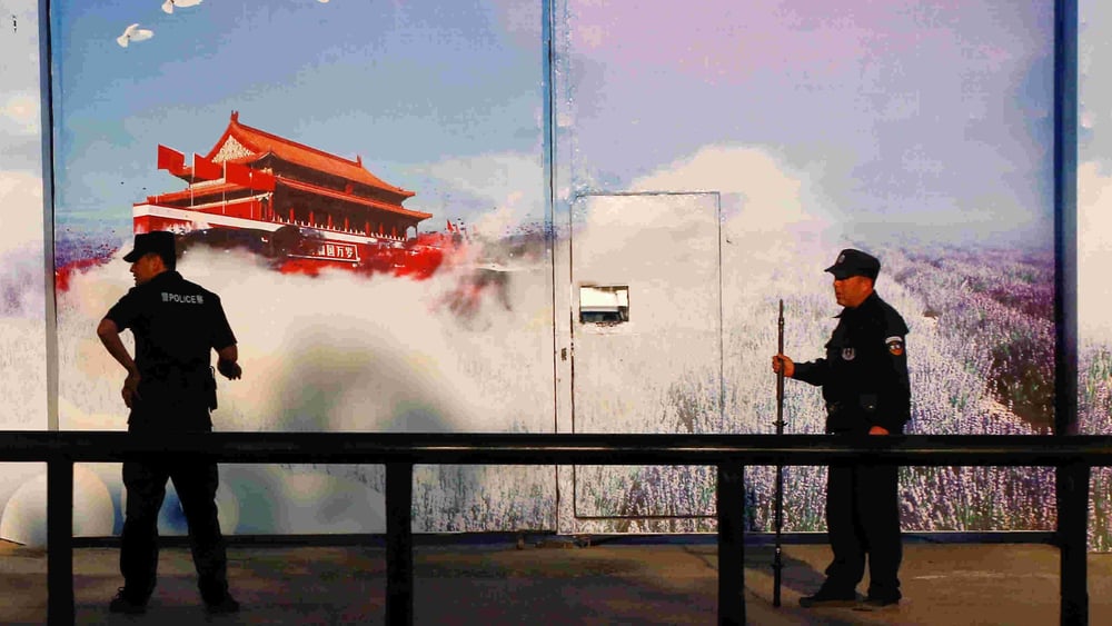 Sicherheitskräfte vor einer Einrichtung, die offiziell als «Berufsbildungszentrum» gilt, im Bezirk Huocheng in Xinjiang. Die hohen Zäune des Zentrums sind mit Propaganda-Bannern versehen, das Eingangstor mit grossen Fotopostern. © REUTERS/Thomas Peter