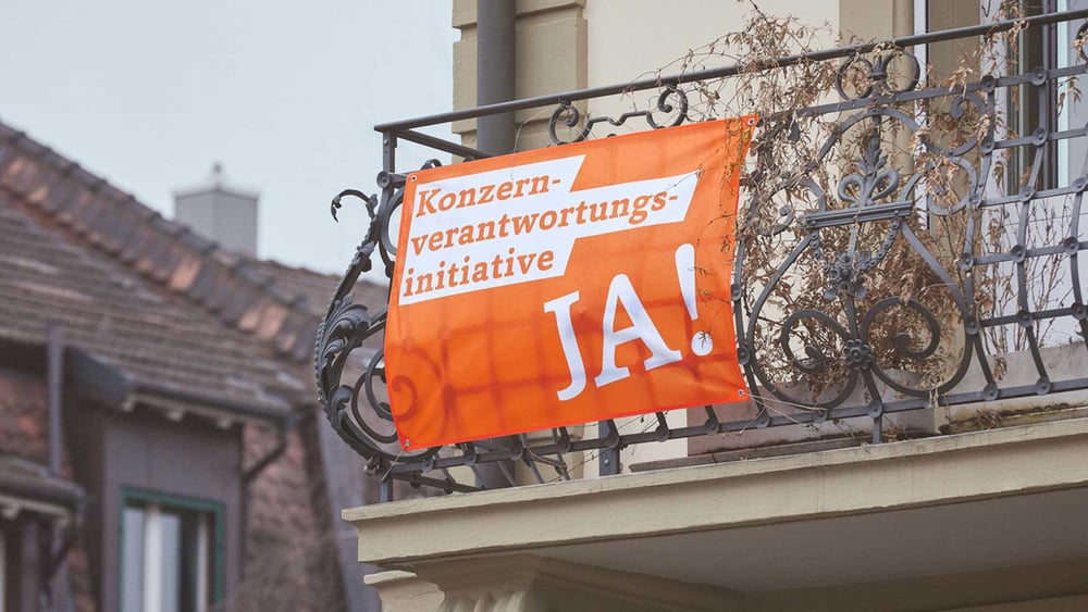 Jetzt sollten sie unbedingt wieder raus, an die Fenster und ie Balkone: Die Fahnen der KVI © konzernverantwortung.ch