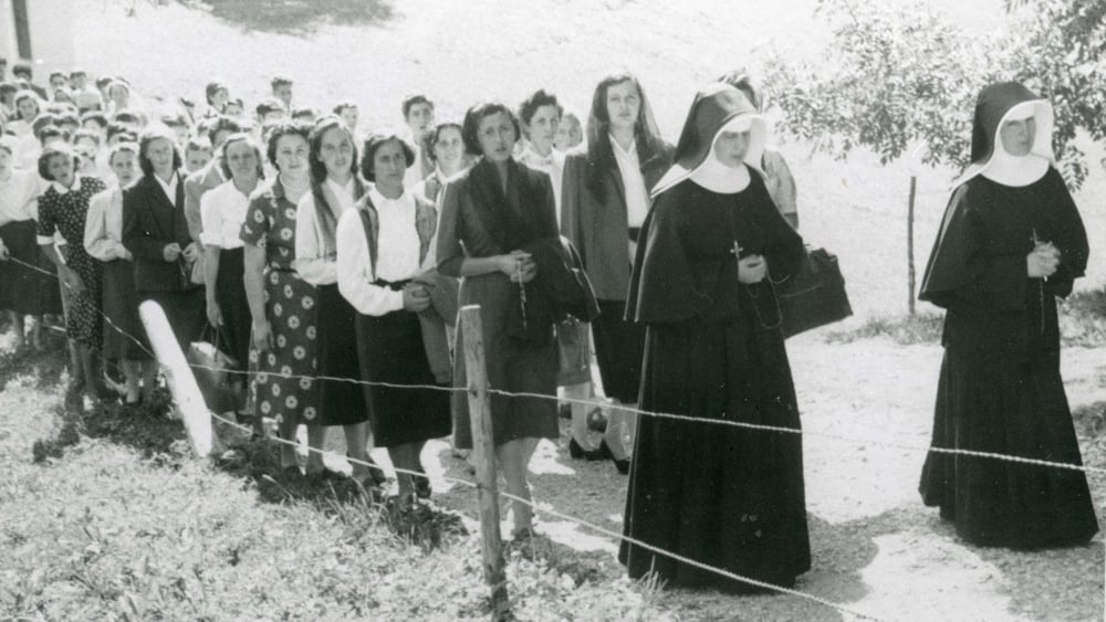 Zwei Nonnen gehen vor einer Gruppe junger Frauen