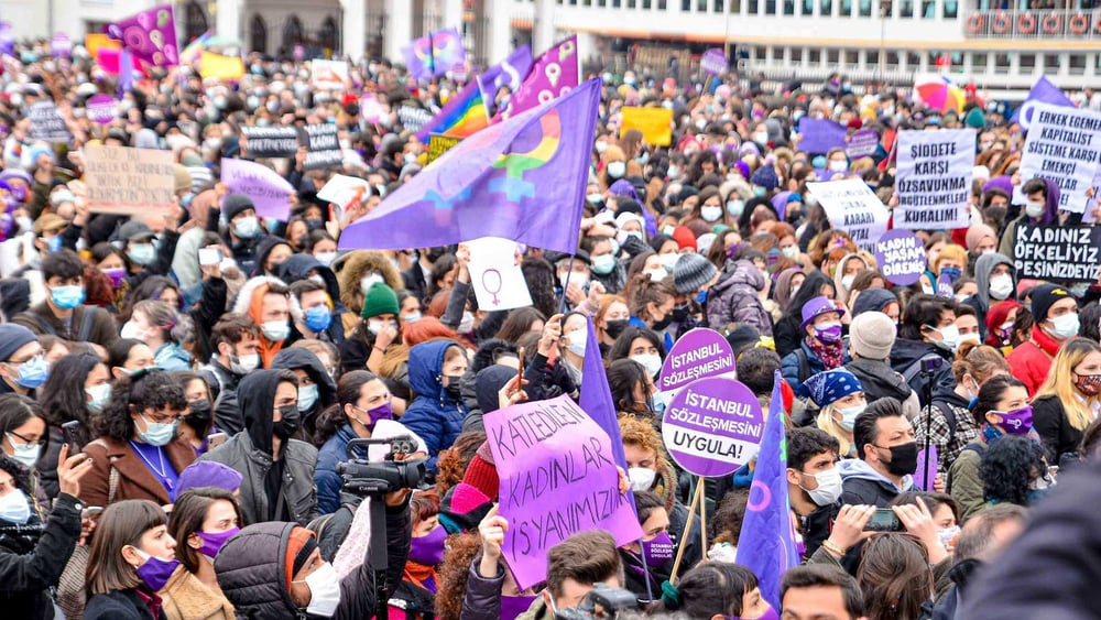 Eine Menschenmenge mit viel Violett und Transparenten in Türkisch