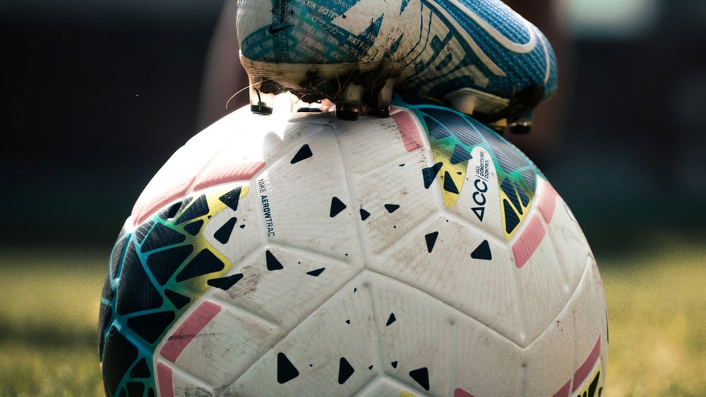 Ein fussballbeschuhter Fuss der auf einem Fussball steht (Ausschnitt)