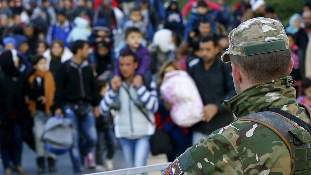 Ein Mitglied der slowenischen Armee beobachtet Migrantinnen und Asylsuchende an der österreichischen Grenze. © Leonhard Foeger/REUTERS
