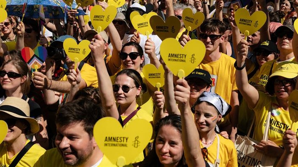 Une foule d'activistes Amnesty tenant des pancartes en forme de coeur.