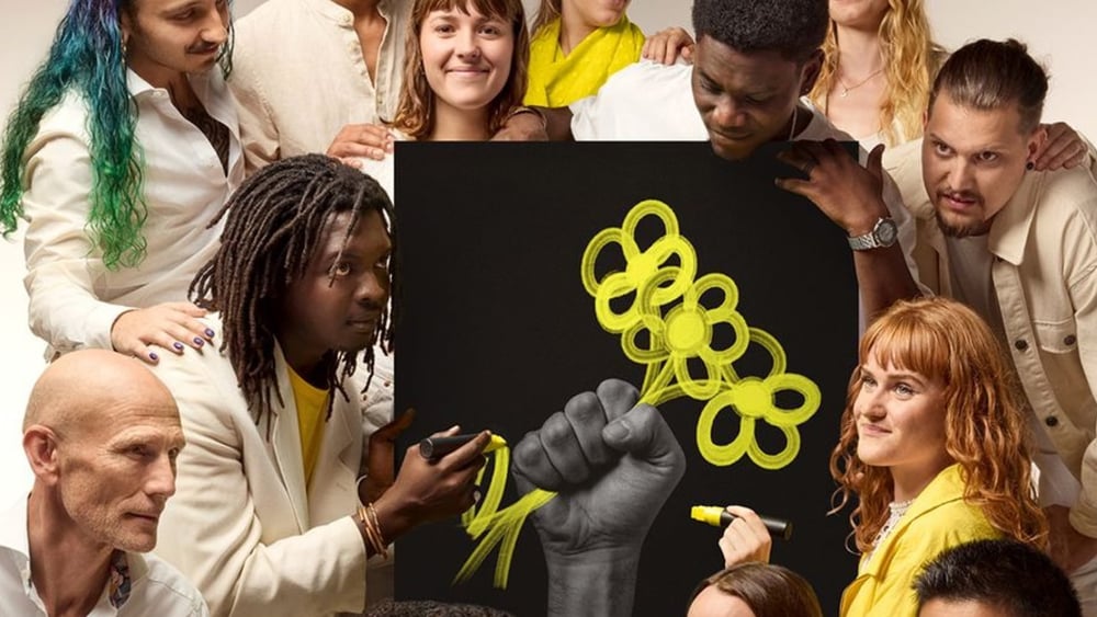 Plusieurs personnes se rassemblent autour de l'affiche de campagne représentant une fleur dessinée