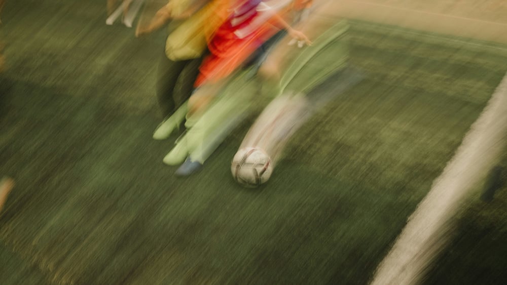 Photo floue de personnes courant après un ballon de football.