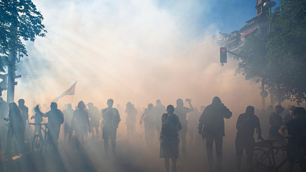 Des manifestant·e·x·s fuient les gaz lacrymogènes.