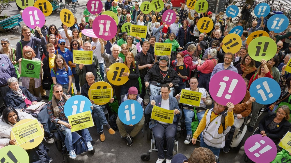 Des militant·e·x·s et des sympathisant·e·x·s lors du lancement de l'initiative, brandissant des pancartes et arborant le symbole de la campagne i!