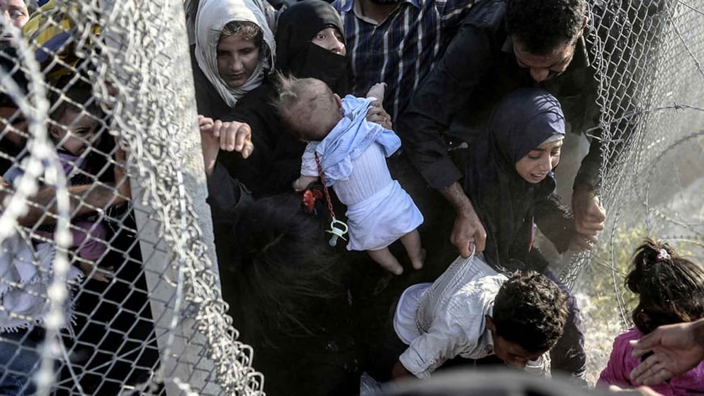 Des Syrien·ne·s profitent de trous dans les barbelés pour entrer illégalement en Turquie à la frontière d'Alçakale, le 14 juin 2015. © Bülent Kiliç - AFP/Getty Images