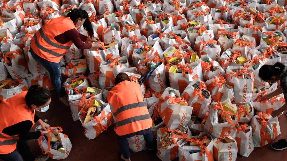 Des bénévoles s’activent lors d’une distribution de colis d’hygiène et de nourriture aux Vernets, à Genève. La crise du coronavirus a fragilisé une partie de la population qui s’est retrouvée en grande difficulté du jour au lendemain. En deux mois, près de 16 000 sacs ont été distribués. ©Getty Images / Fabrice Coffrini