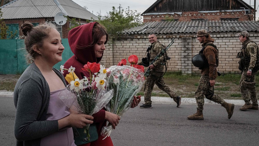 Au milieu des bombardements, la vie de la population ukrainienne suit son cours. Dans le Donbass, des soldats ukrainiens croisent deux adolescentes, qui apportent des fleurs pour célébrer un anniversaire. © Yasuyoshi CHIBA/AFP/KEYSTONE