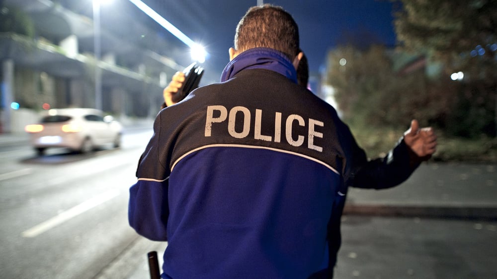 Un policier de la ville de Lausanne fouille un suspect. © Dominic Favre/KEYSTONE