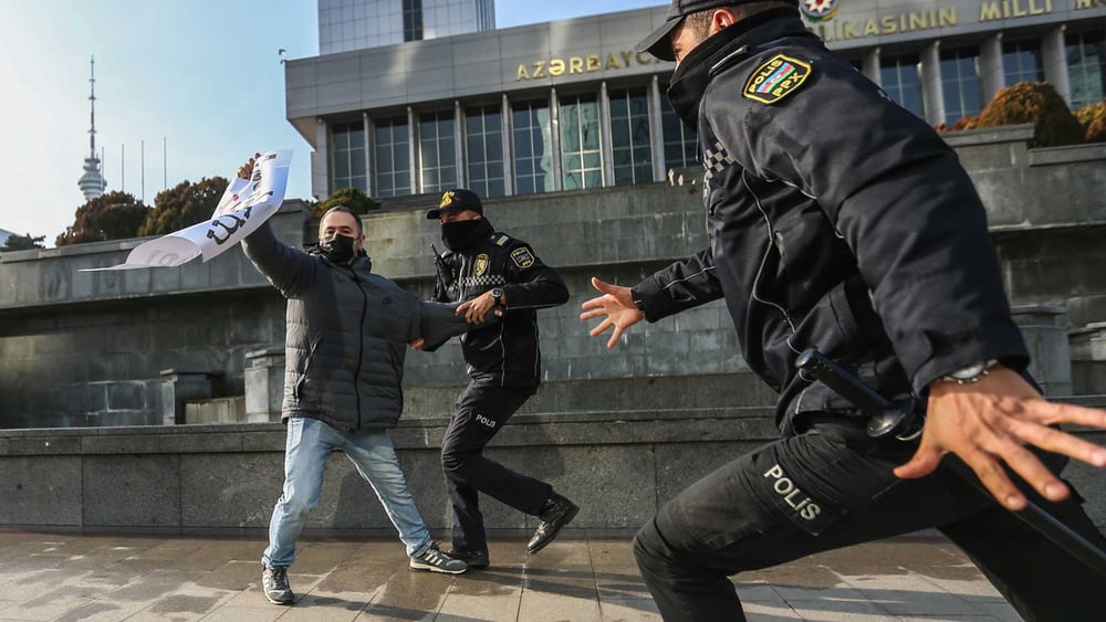 Le directeur de la publication en ligne «Abzas Media», Ulvi Hasanli, est vu alors que la police confisque une affiche sur laquelle on peut lire «Le journalisme n'est pas un crime» lors d'un rassemblement de journalistes. (Bakou/Azerbaïdjan 28.12.2024) © Aziz Karimov/Getty Images