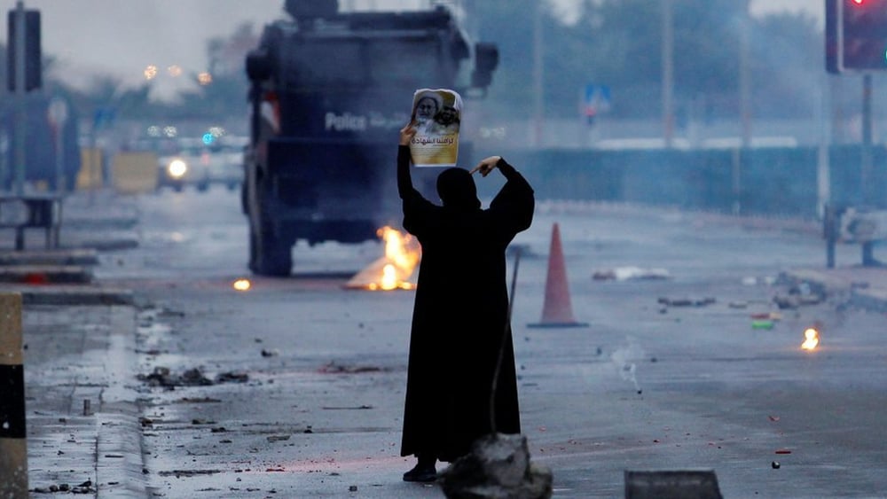 Une manifestante montre une photo d'un prêtre chiite à un convoi de policiers. © REUTERS/Hamad I Mohammed
