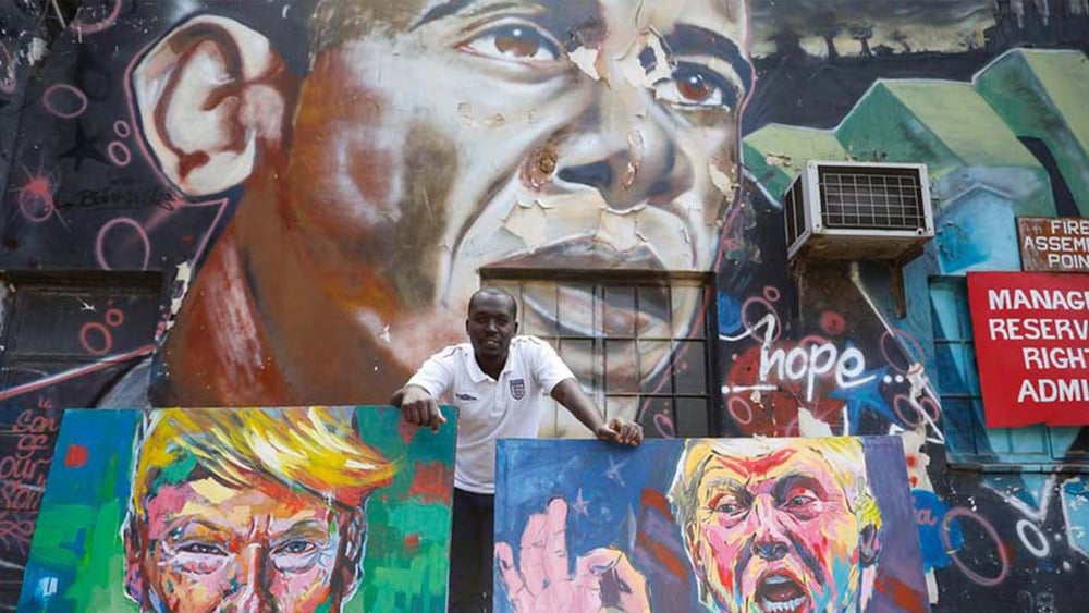 L’artiste kenyan Yegonizer et ses portraits de Donald Trump, devant une oeuvre murale de Bankslave représentant Obama. © Keystone/EPA/DAI KUROKAWA