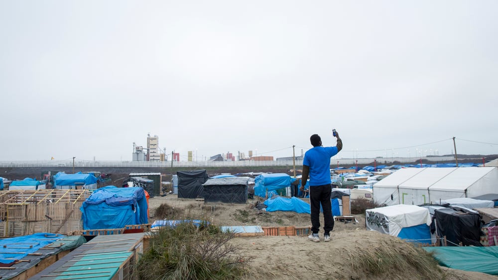 Un résident de la «Jungle» à Calais cherchant un signal réseau sur son téléphone.  © Richard Burton/Amnesty International