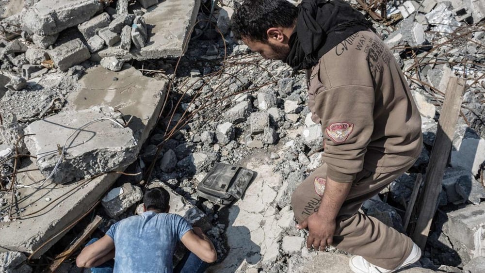 Avec l'aide d'un ami, un survivant examine ce qu'il reste de sa maison après une attaque aérienne qui a détruite Al-Sekar le 14 mars, à l'est de Mossoul. © Andrea DiCenzo/Amnesty International