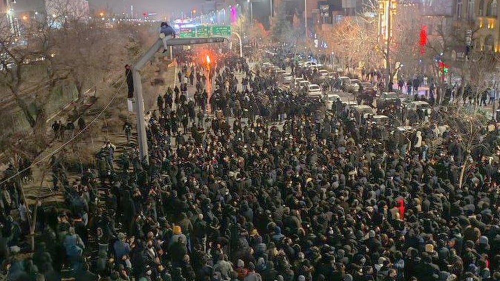 Une grande manifestation dans une rue, le soir.