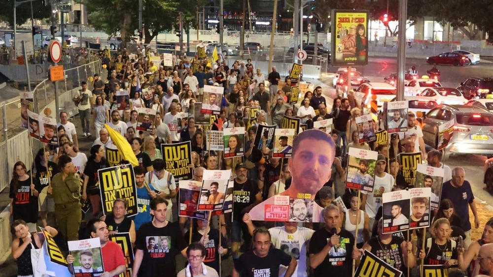 Des proches d'otages israéliens et leurs soutiens brandissent des photos et des pancartes lors d'une manifestation appelant à agir pour obtenir la libération des otages détenus à Gaza depuis le 7 octobre 2023, devant le siège du ministère israélien de la Défense à Tel-Aviv, en Israël, le 6 août 2025. © Jack Guez/AFP via Getty Images