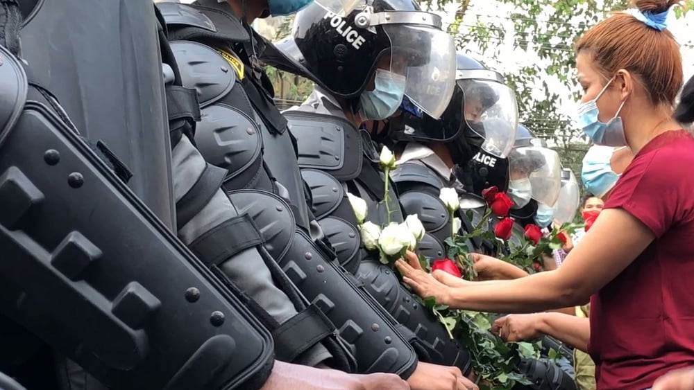 Des activistes offrent des fleurs aux forces de la police, lors d'une manifestation à Yangon © Maung Sun / wikimedia