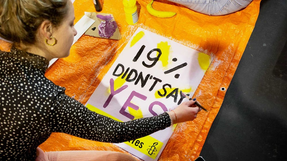 Une activiste d'Amnesty à Amsterdam peint un poster pour la campagne «Let's talk about Yes». © www.mariekevandervelden.com