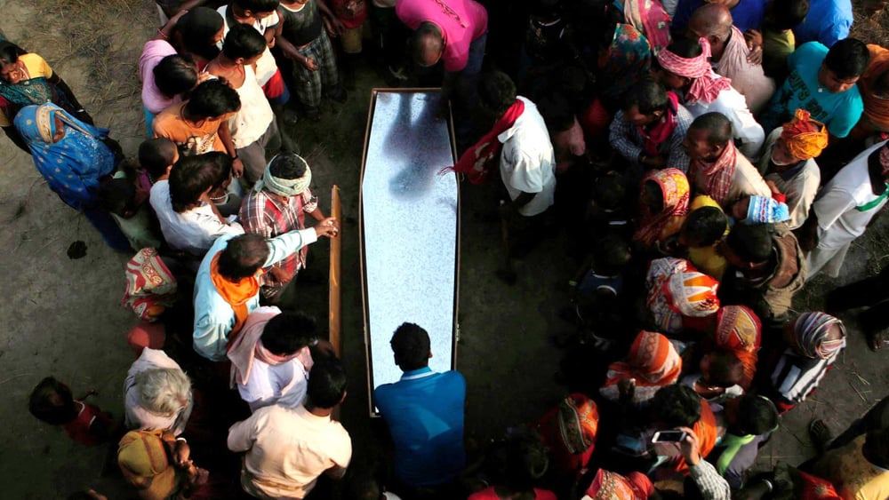 Dans un village népalais, des proches et habitant·e·x·s se rassemblent autour du cercueil d'un travailleur migrant, décédé dans son sommeil au Qatar. © Niranjan Shrestha/AP/Shutterstock
