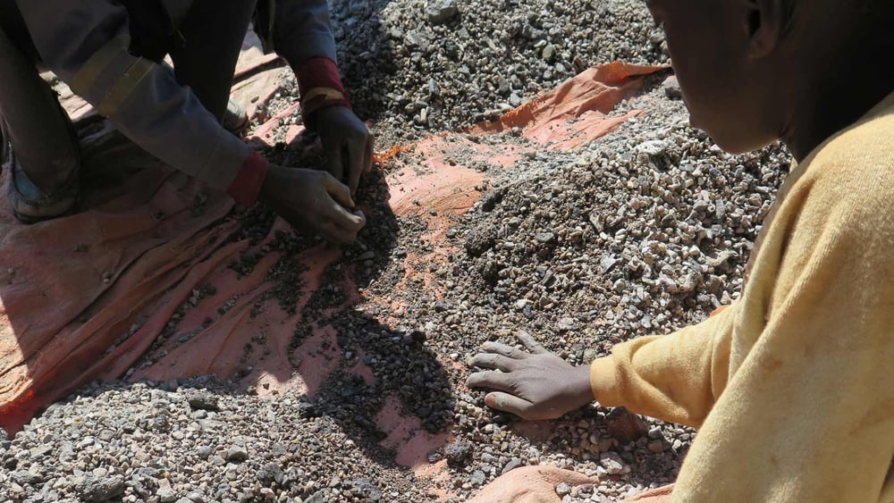 Charles, 13 ans, trie des pierres contenant du cobalt sur la rive du lac Malo Kapata en RDC. © Amnesty International.