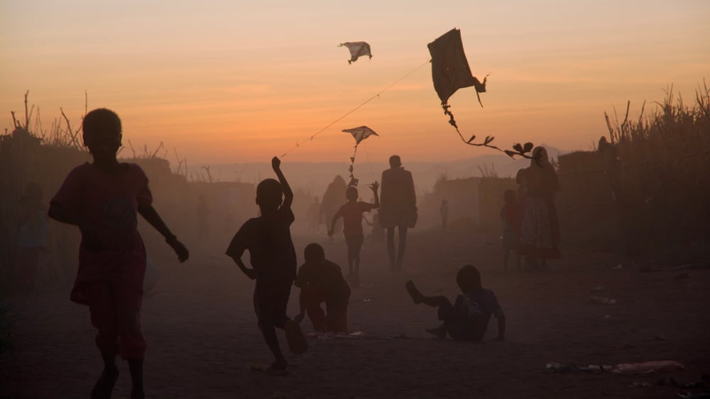Des enfants jouent avec des cerfs-volants au coucher du soleil.