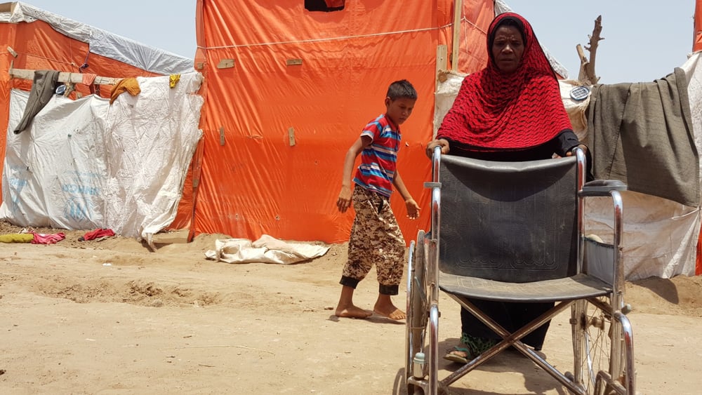 Sur cette photo prise au camp de Mishqafa, Lahj, le 11 juin 2019, Lola Ahmed, la mère d'une jeune fille de 16 ans ayant une déficience physique et intellectuelle, lutte pour pousser un fauteuil roulant donné à sa fille. © Amnesty International