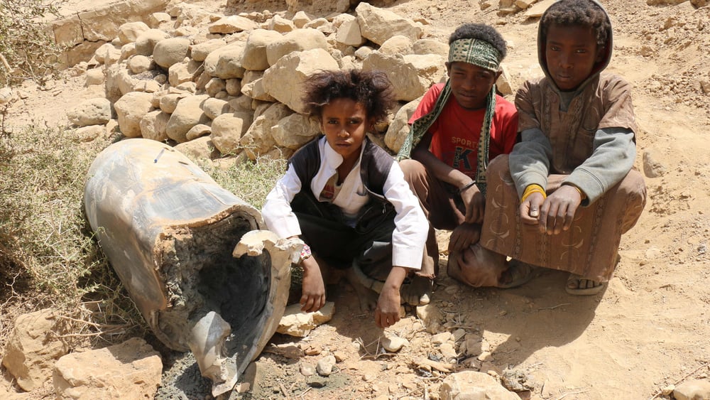 Des enfants dans la ville de Saada au Yémen assis à côté d'un obus. © Amnesty International