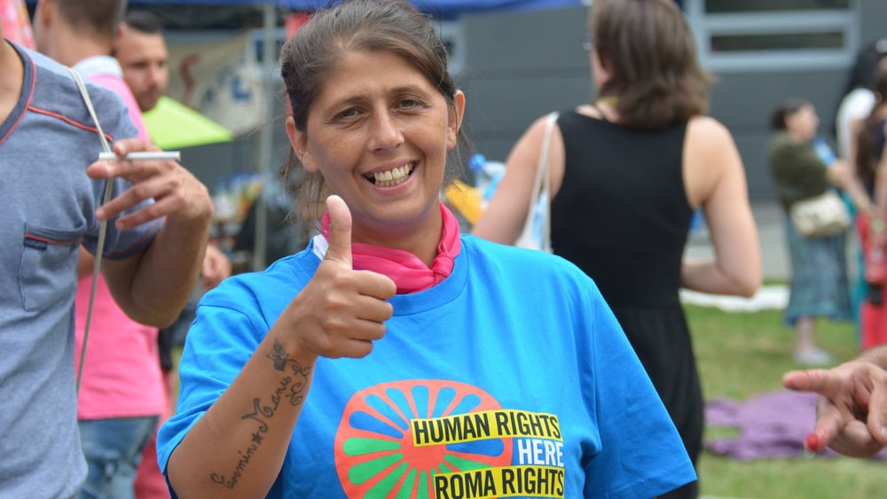 Une militante rom originaire de Cluj, en Roumanie, lors d'une cérémonie commémorative du génocide des Roms à Auschwitz en 2014. Plus d'un millier de jeunes, Roms et non-Roms, se sont réunis pour commémorer les victimes roms et sintis du génocide des Roms, rencontrer des survivants et en apprendre davantage sur ce chapitre sombre de l'histoire européenne, tout en cherchant des moyens de lutter contre les préjugés, la discrimination et le racisme dont ils sont encore victimes aujourd'hui. © Amnesty International