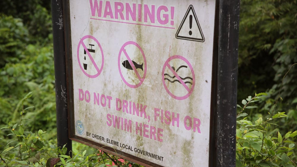 Un panneau dans la jungle qui, en anglais, met en garde contre le fait de boire l'eau, de s'y baigner ou d'y pêcher.
