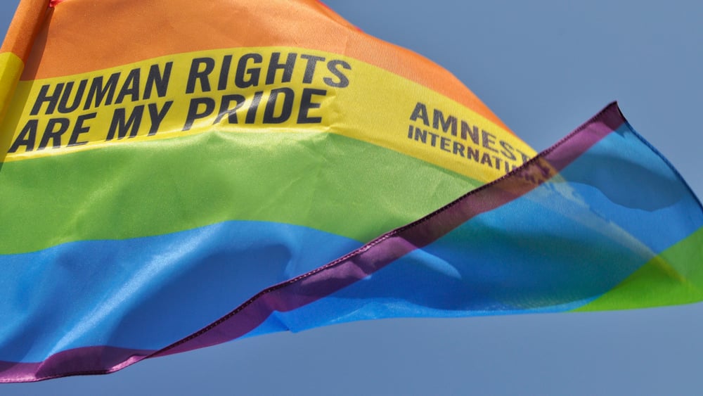 Gay-Pride-Fahne weht im Wind mit den Worten: Amnesty International – Menschenrechte sind mein Stolz.