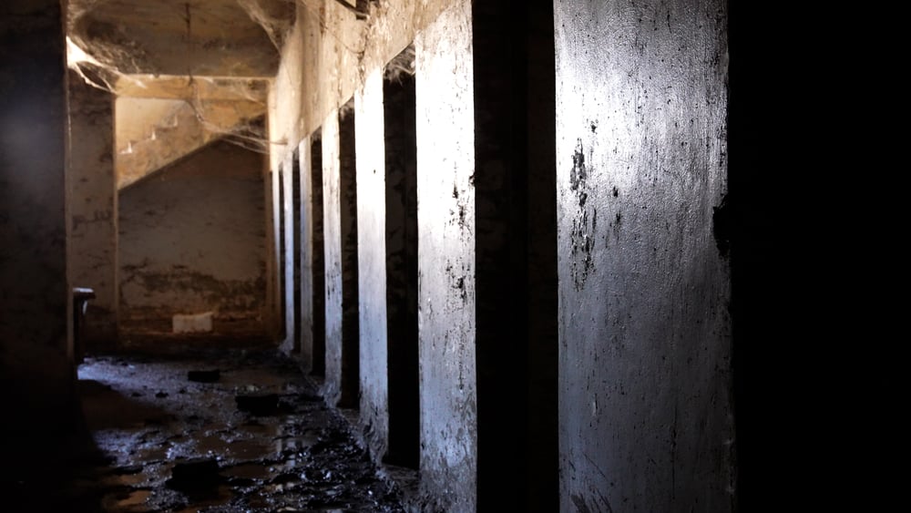Un couloir sombre et sale avec des portes qui menaient probablement à des cellules.