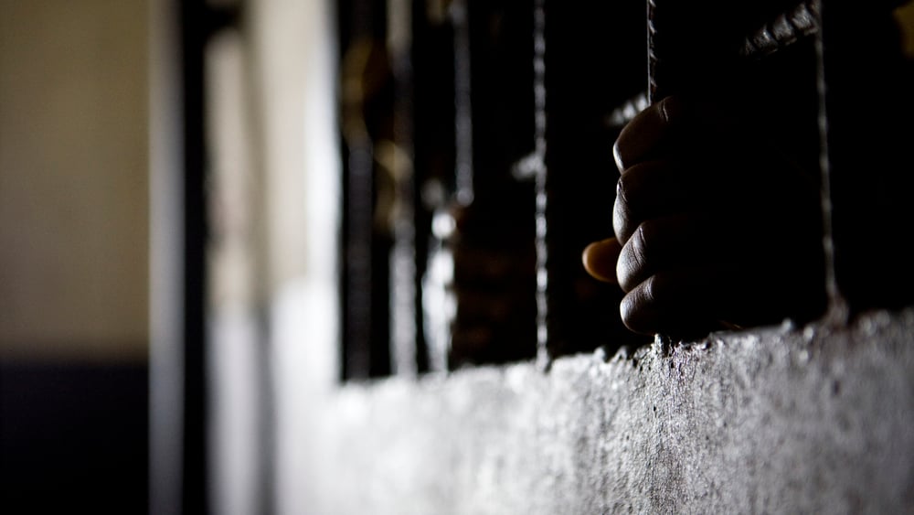 Deux mains agrippées aux barreaux