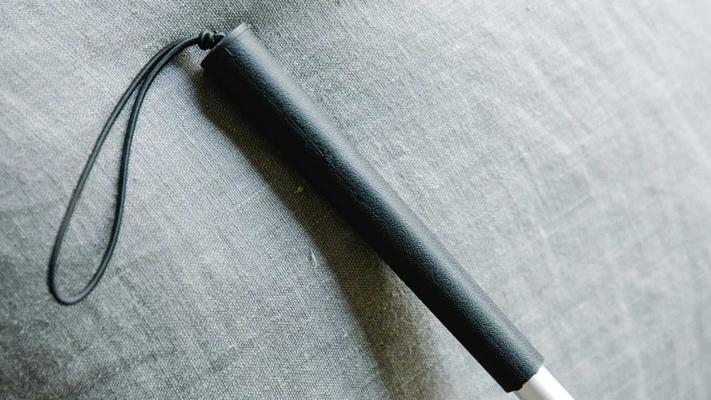 La parte superiore di un bastone per disabili su un panno grigio.