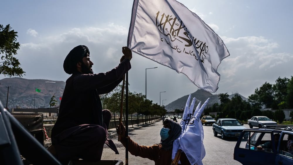 Il mollah Esmatullah Khadir sventola una bandiera talebana dopo la caduta di Kabul, il 20 agosto 2021 © Marcus Yam / Los Angeles Times