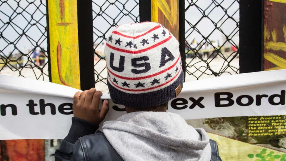 Un bambino guarda Tijuana attraverso il muro della frontiera che separa il Messico dagli Stati Uniti © Amnesty International / Sergio Ortiz Borbolla